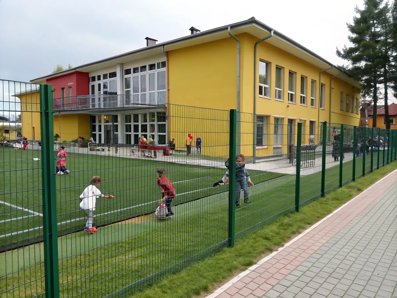 A wide shot showcasing various colors and styles of PVC coated chain link fences installed in different settings, such as a school playground, a sports field, and a garden, highlighting the design options.
