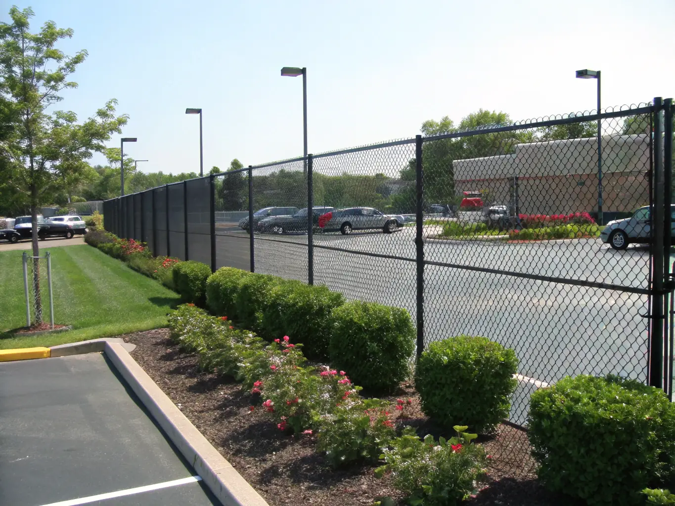 A medium shot of a PVC coated chain link fence installed around a commercial property, withstanding harsh weather conditions such as rain and wind, demonstrating its weather resistance.