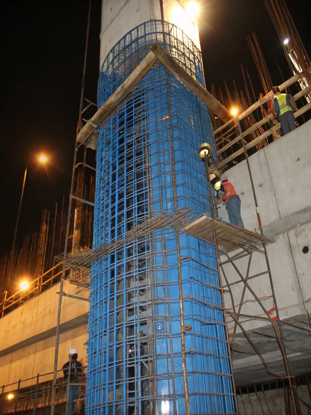 A construction site featuring hexagonal wire mesh reinforcing concrete structures, demonstrating its role in enhancing the durability and stability of buildings. The scene is active with workers and equipment.