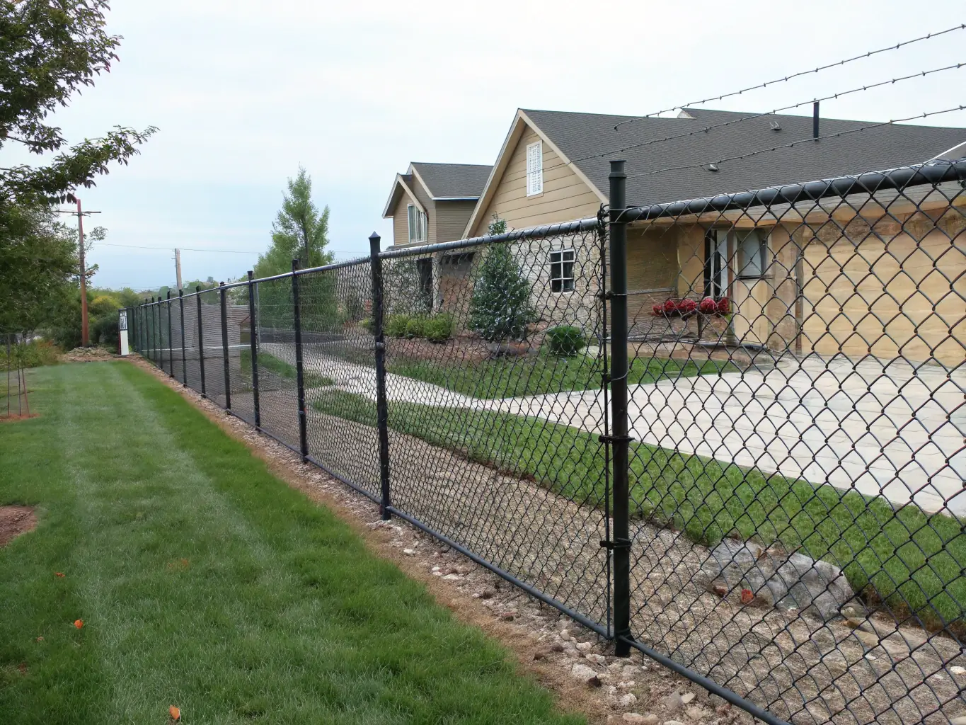 A detailed close-up shot of a chain-link fence topped with barbed wire, illustrating its effectiveness as a perimeter deterrent in a high-security environment.