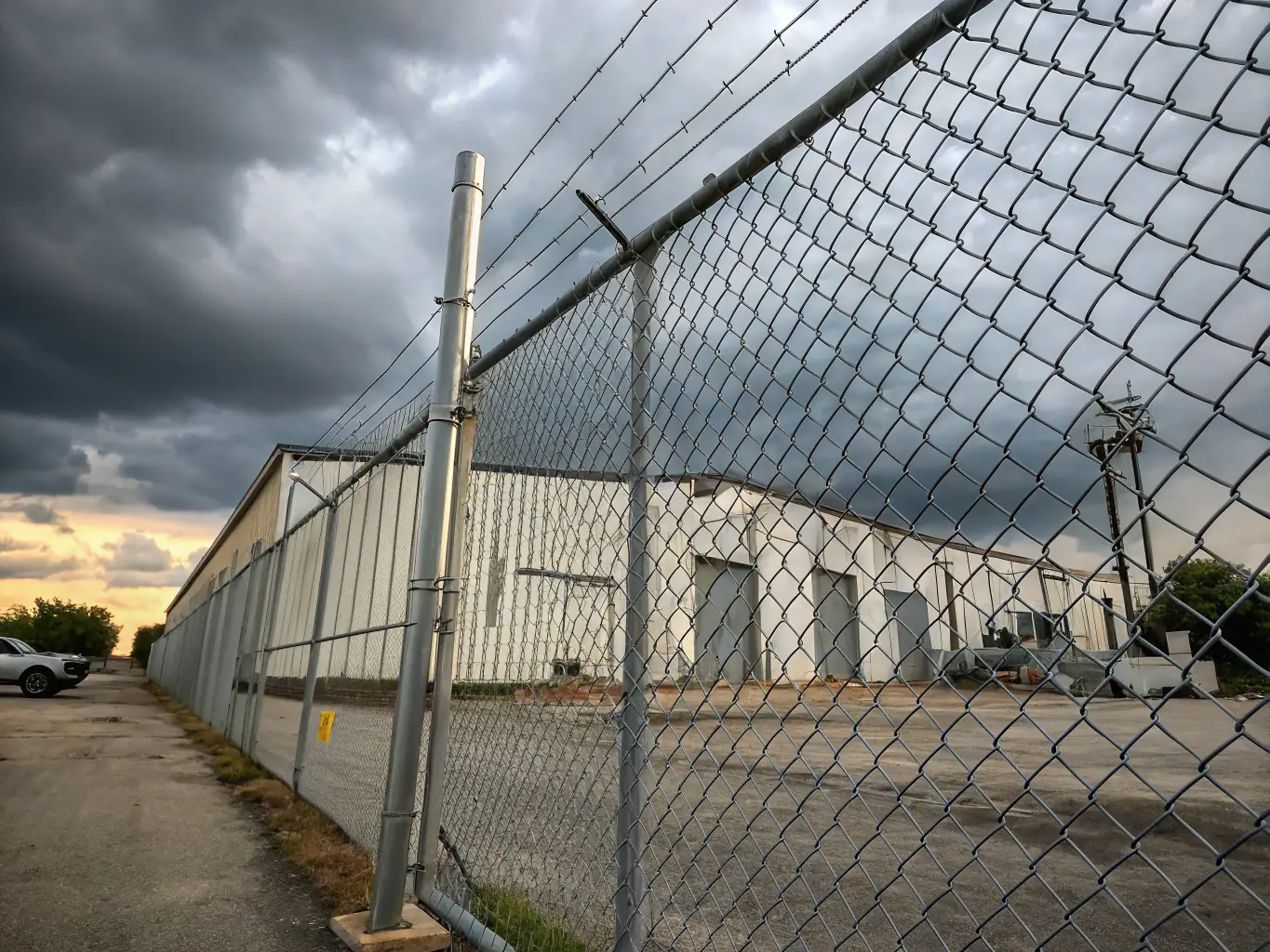 A high-resolution image showcasing a galvanized chain link fence surrounding a commercial property, emphasizing its durability and wide coverage area.