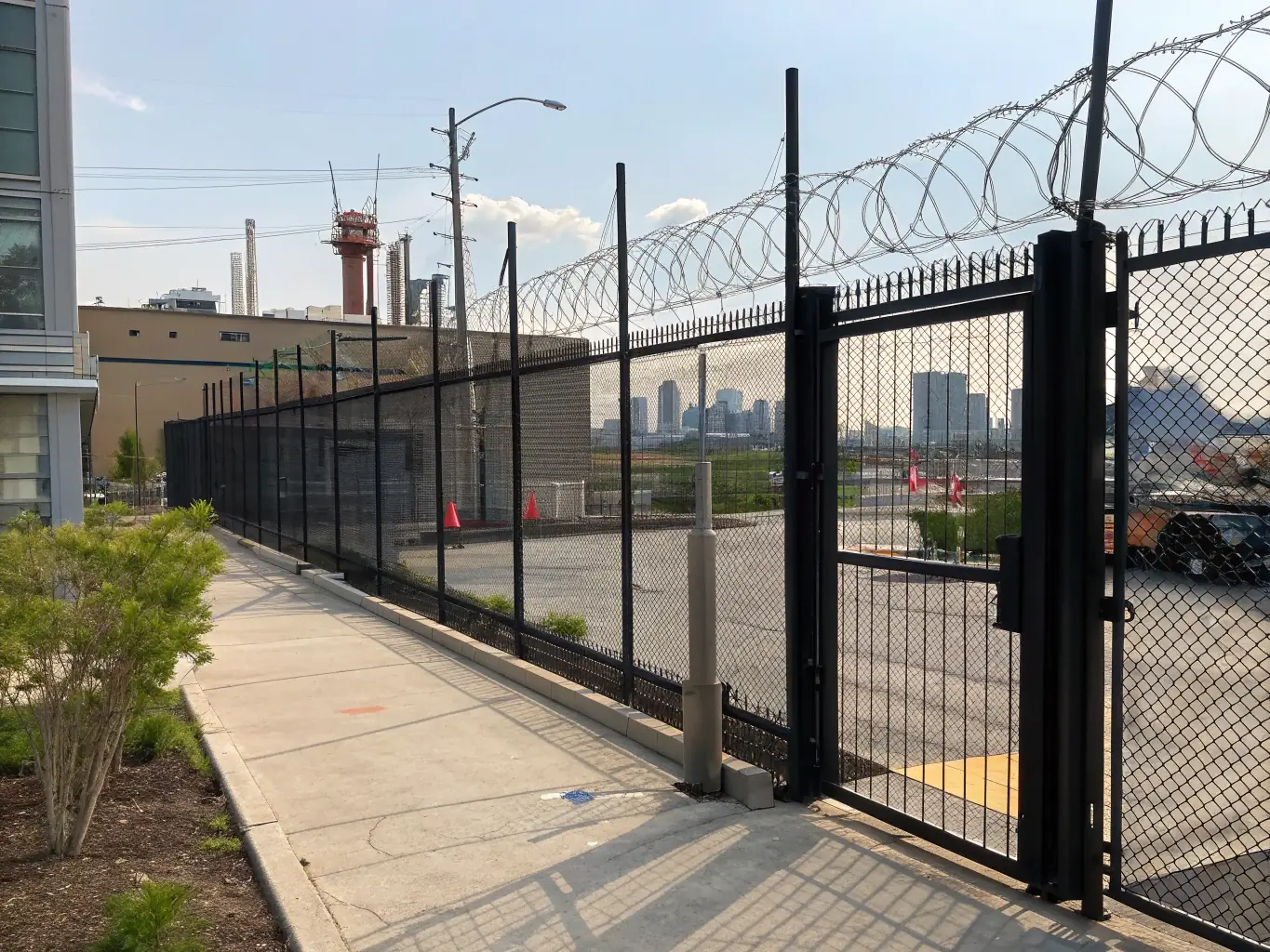 A high-security perimeter featuring MeshForge welded wire fences topped with barbed wire, guarding a critical infrastructure facility against potential intrusions.