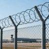 Airport perimeter protected by chain link fence with razor wire