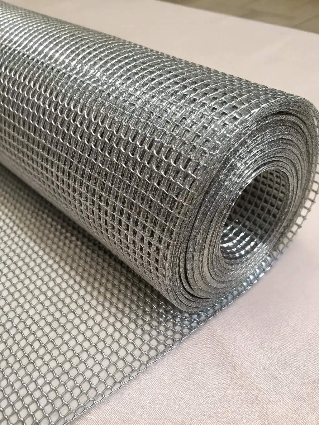 Close-up photo of stainless steel square woven wire mesh, showing uniform square openings and metallic luster, set against a clean white industrial background for a technical product page.