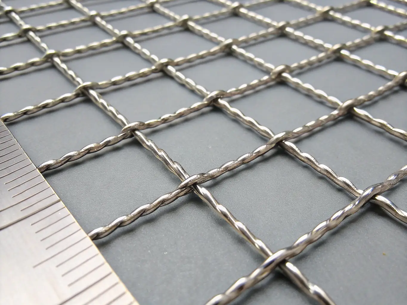 A close-up photograph of stainless steel filter cloth showing fine woven wire mesh structure, highlighting uniform apertures and metallic sheen, suitable for illustrating material quality and weave precision on an industrial B2B website.
